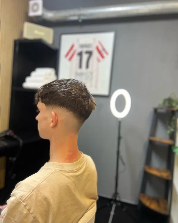 Krátký pánský střih buzz cut s výraznou vyholenou linkou a čistým fadem v Ori's Barber Shop.
