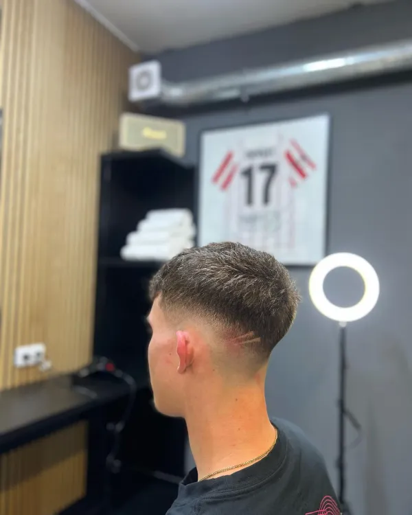 Moderní pánský střih textured crop s jemným vyholeným detailem (hair design) na straně.