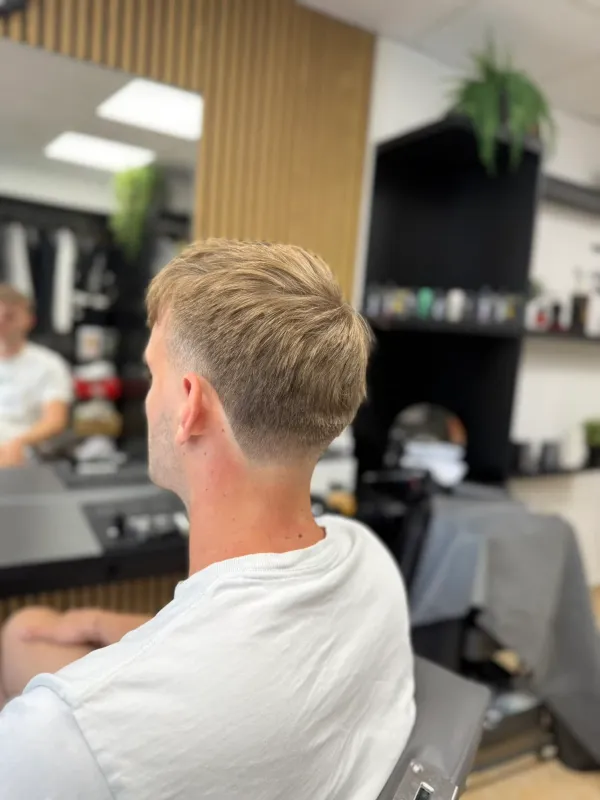Pánský střih na blond vlasech s nízkým fadem od Ori's Barber Shop.